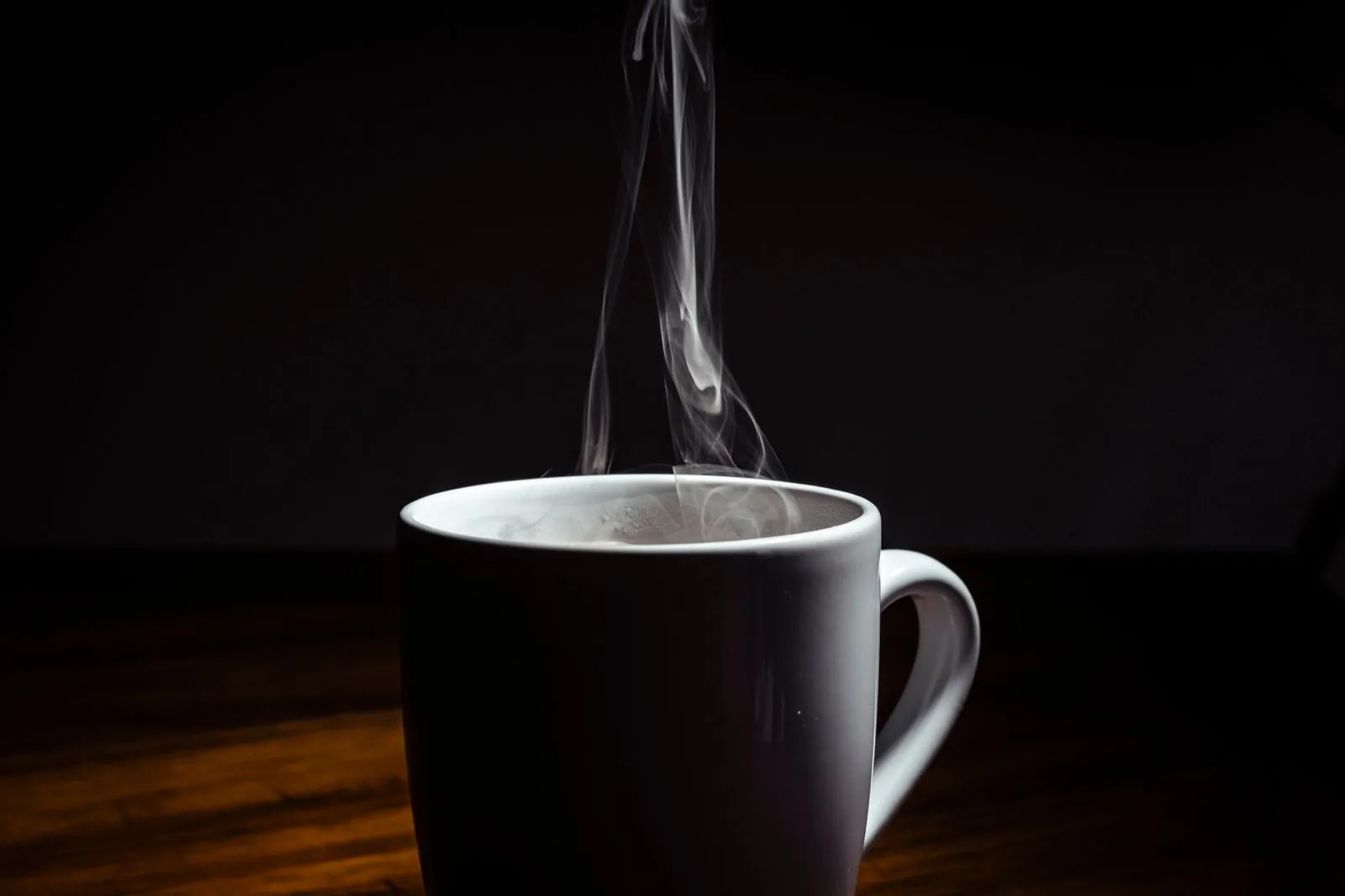 White ceramic mug with rising steam on a dark background